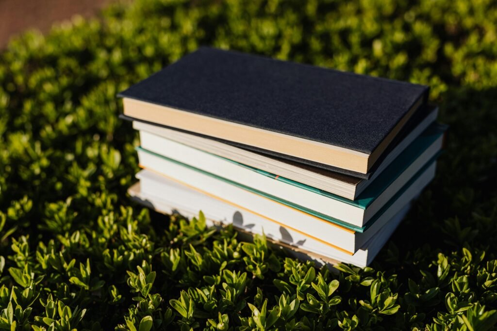 A harmonious close-up of a stack of books resting on lush green foliage, symbolizing knowledge and nature.